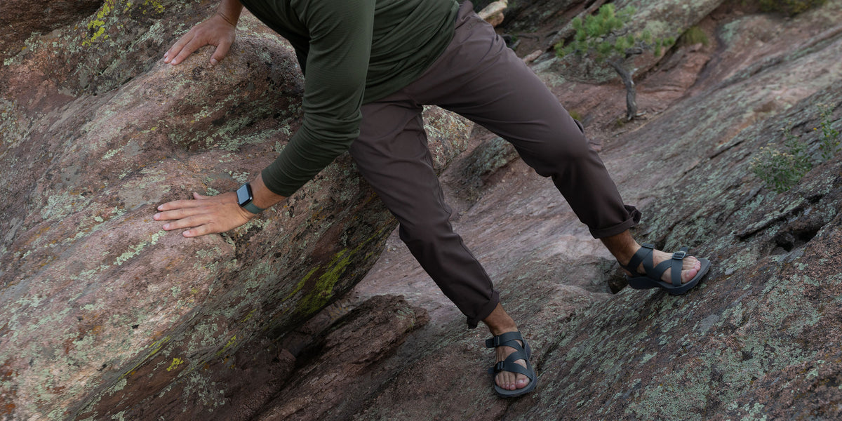Man wearing Redway hiking sandals with arch support climbing over boulders