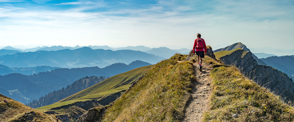 Man walking along a trail in a scenic mountain landscape