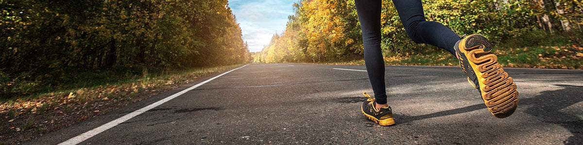A runner wearing insoles for running shoes running down a road on a sunny day